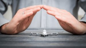 Miniature plane model on a wooden desk, with a man covering it with his hands, and a grey shirt on.