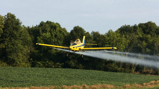 Aircraft industry risks - small crop-duster in action over a rural field in New Zealand.
