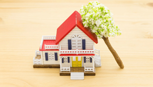 A toy house with a toy tree cantilevered on top of it.