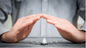 Aircraft industry risks: person’s hands forming a protective gesture over a small model plane